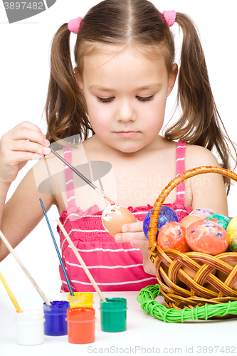 Image of Little girl is painting eggs preparing for Easter