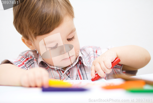 Image of Little boy is drawing on white paper