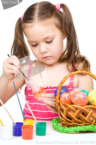 Image of Little girl is painting eggs preparing for Easter