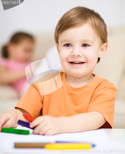 Image of Little boy is drawing on white paper