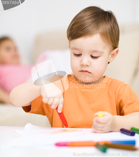 Image of Little boy is drawing on white paper