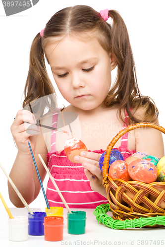 Image of Little girl is painting eggs preparing for Easter