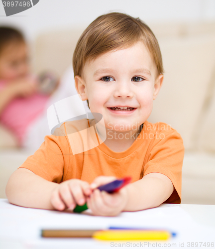 Image of Little boy is drawing on white paper