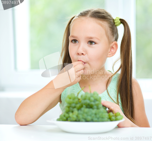 Image of Cute little girl is eating green grapes