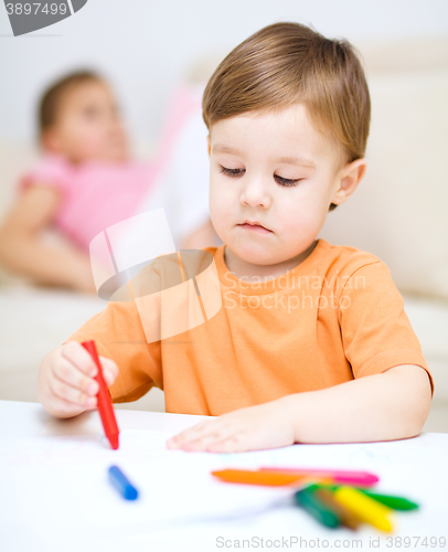 Image of Little boy is drawing on white paper