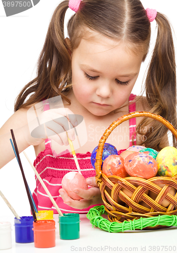 Image of Little girl is painting eggs preparing for Easter