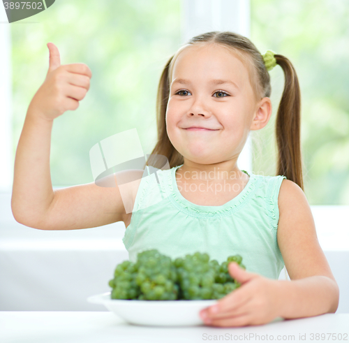 Image of Cute little girl is eating green grapes