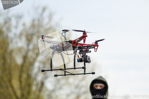 Image of Man in mask operating a drone with remote control.