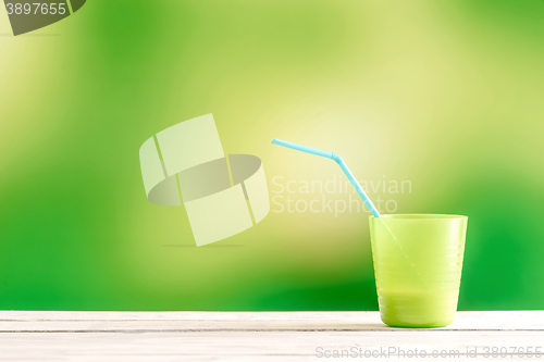 Image of Green cup with a blue straw