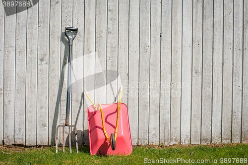 Image of Pitchfork and a wheelbarrow in a garden