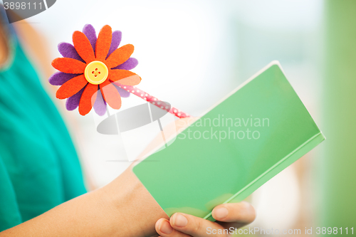 Image of Woman Writing in Notebook with Flower Pencil