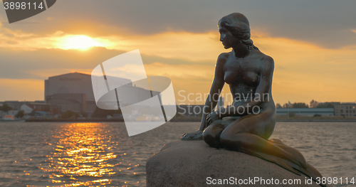 Image of Mermaid statue on the stone in sea at sunset