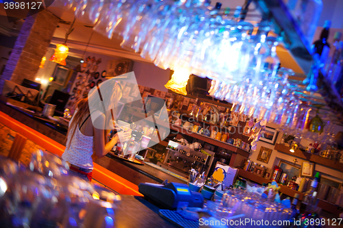 Image of Young woman enjoying a drink in a cocktail bar