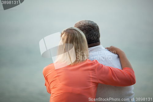 Image of Couple with Arms Around Each Other Admiring Sunset