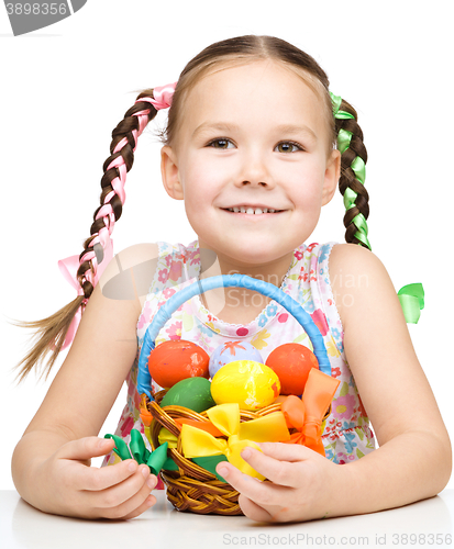 Image of Little girl with basket full of colorful eggs