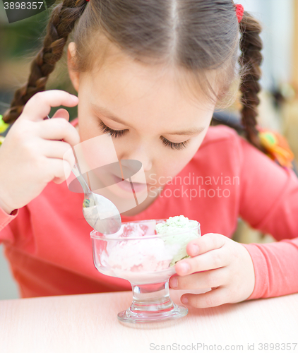 Image of Little girl is eating ice-cream in parlor