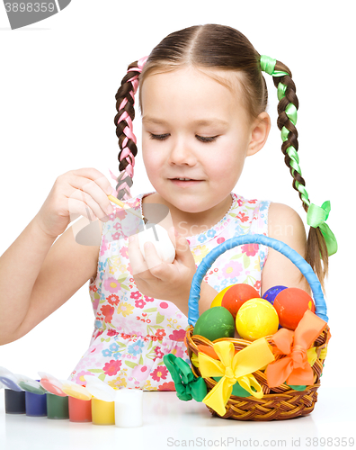 Image of Little girl is painting eggs preparing for Easter