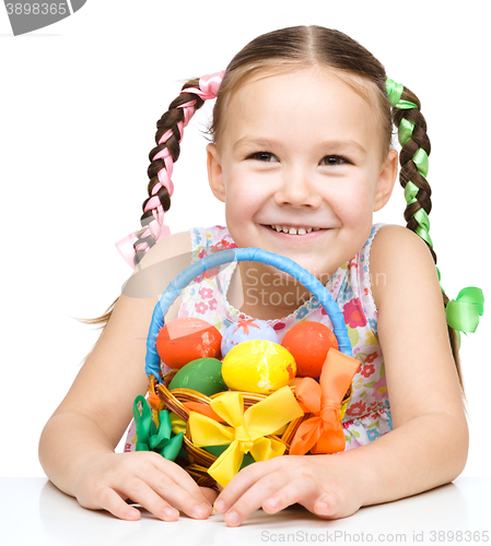 Image of Little girl with basket full of colorful eggs