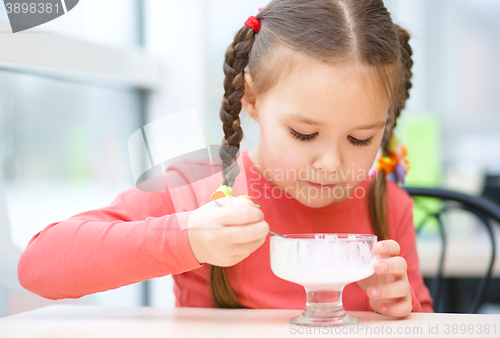 Image of Little girl is eating ice-cream in parlor