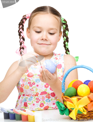 Image of Little girl is painting eggs preparing for Easter