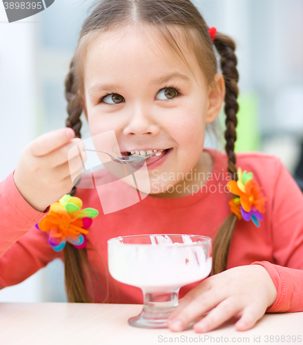 Image of Little girl is eating ice-cream in parlor