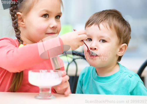 Image of Girl is feeding his little brother with ice-cream