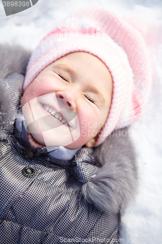 Image of Little girl is laying on a snow