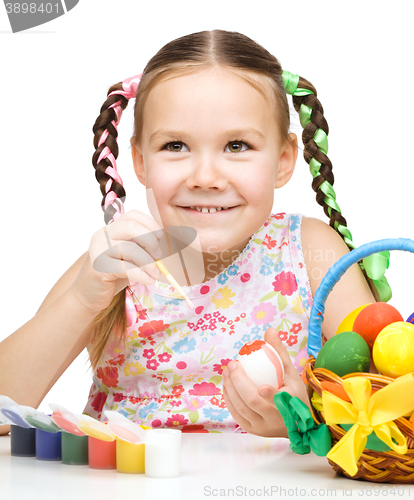 Image of Little girl is painting eggs preparing for Easter