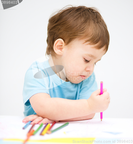 Image of Little boy is drawing on white paper