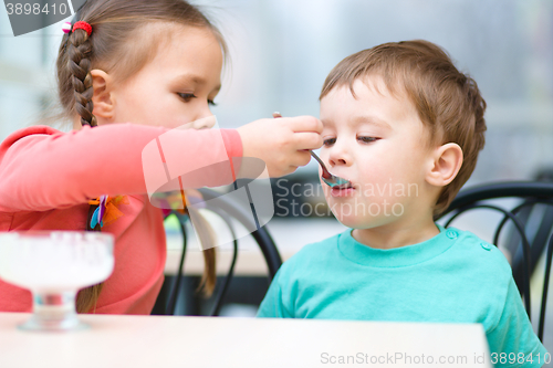 Image of Girl is feeding his little brother with ice-cream