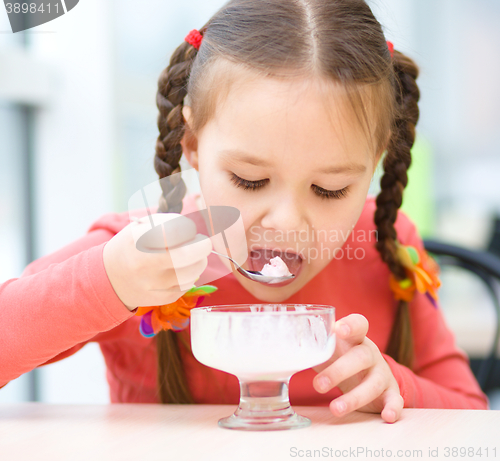 Image of Little girl is eating ice-cream in parlor