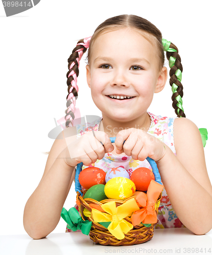 Image of Little girl with basket full of colorful eggs