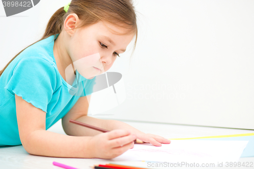 Image of Little girl is drawing using pencils