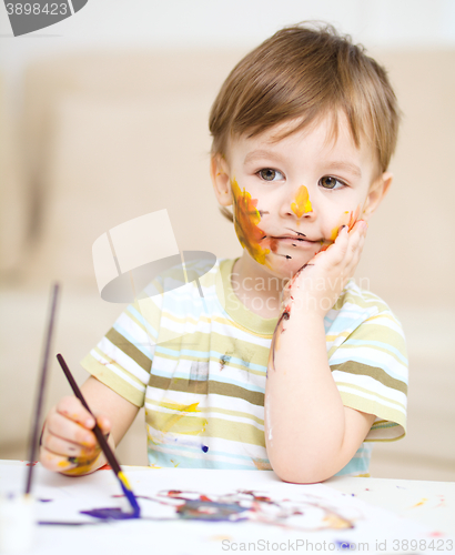 Image of Little boy is playing with paints