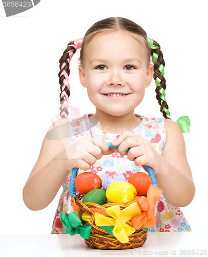 Image of Little girl with basket full of colorful eggs