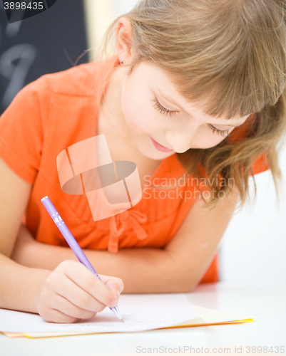 Image of Little girl is writing using a pen