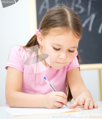 Image of Little girl is writing using a pen
