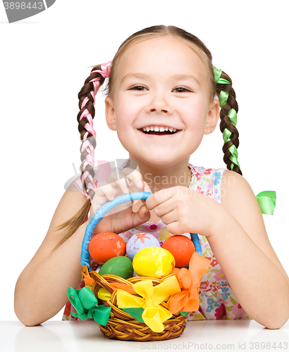 Image of Little girl with basket full of colorful eggs