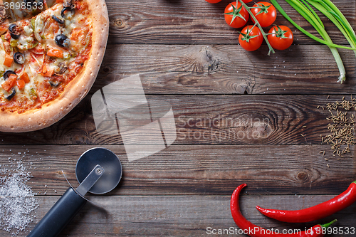 Image of Tasty pizza with ingridients on a wooden board.