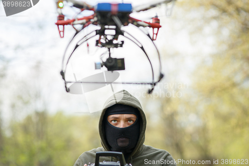 Image of Man in mask operating a drone with remote control.