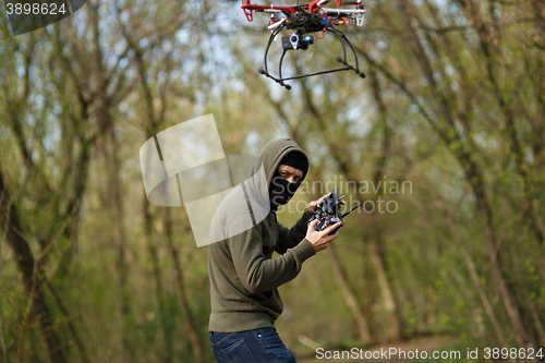 Image of Man in mask operating a drone with remote control.