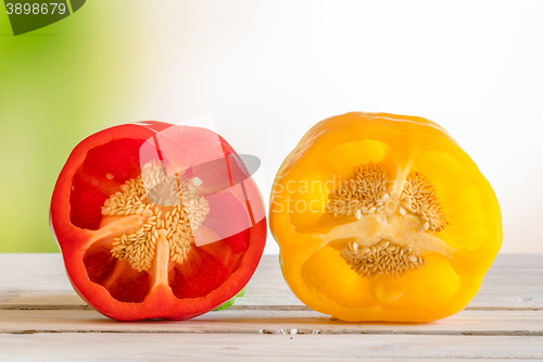 Image of Red and yellow pepper with seeds on a wooden table