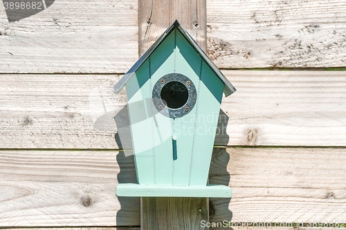 Image of Blue birdhouse on a wooden fence