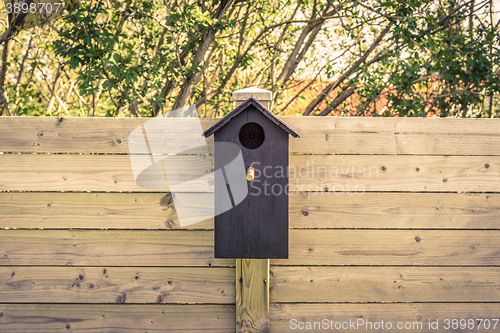 Image of Black bird house on a fence