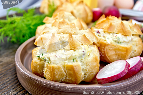 Image of Appetizer of radish and cheese in profiteroles on clay plate wit