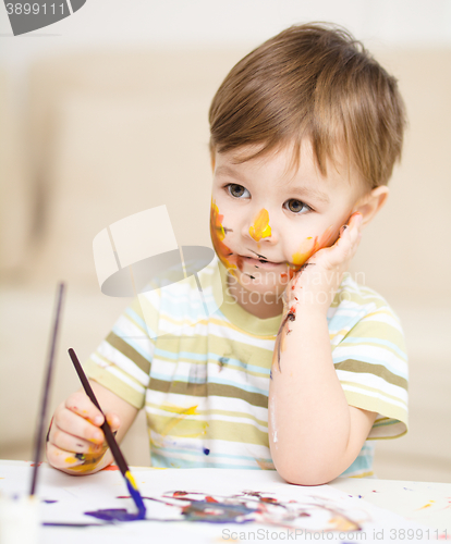 Image of Little boy is playing with paints