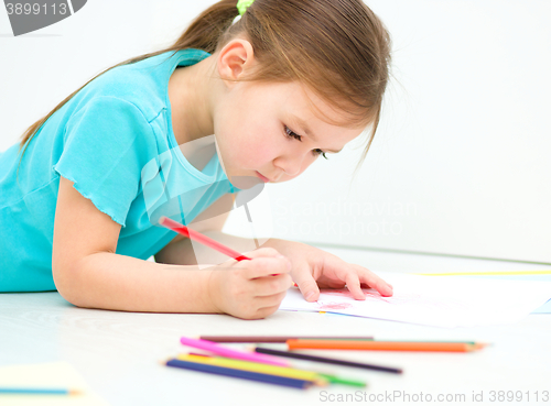 Image of Little girl is drawing using pencils