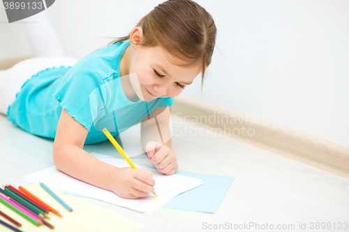 Image of Little girl is drawing using pencils