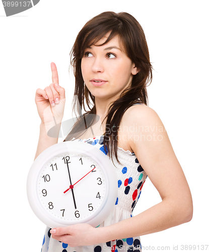 Image of Young woman is holding big clock