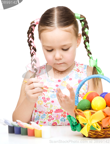 Image of Little girl is painting eggs preparing for Easter